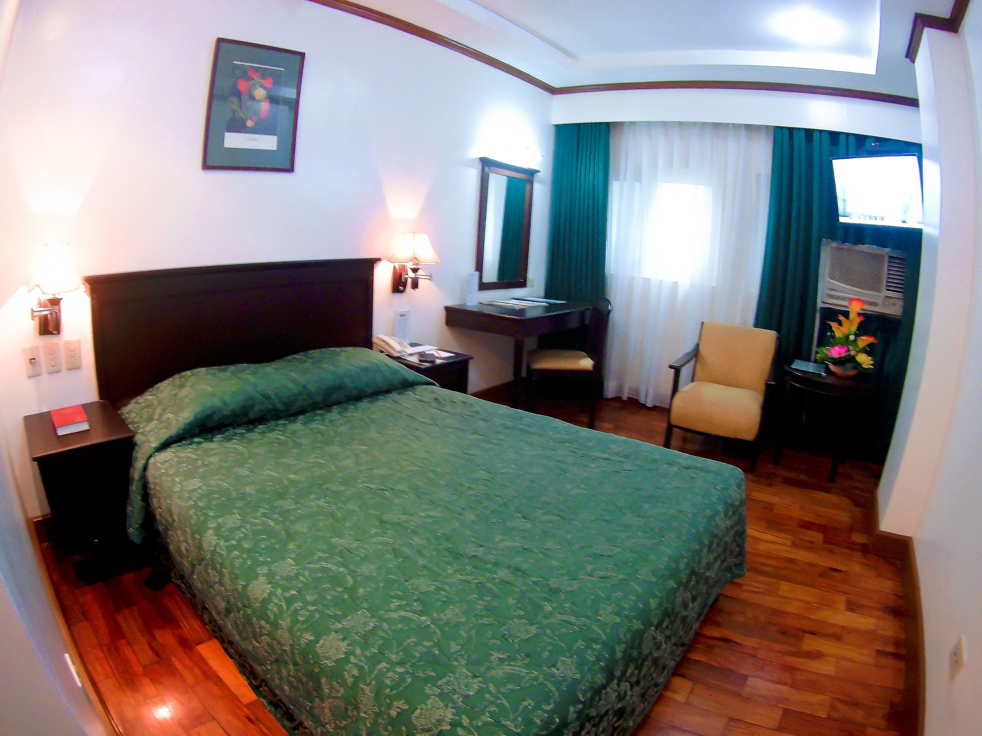 Habitación de hotel con cama, escritorio, silla y televisor.