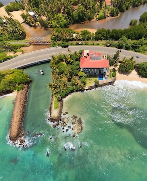 An aerial view of a coastal property with a beach, a small pier, and a building with a red roof. - Gartons Cape (Ahangama)