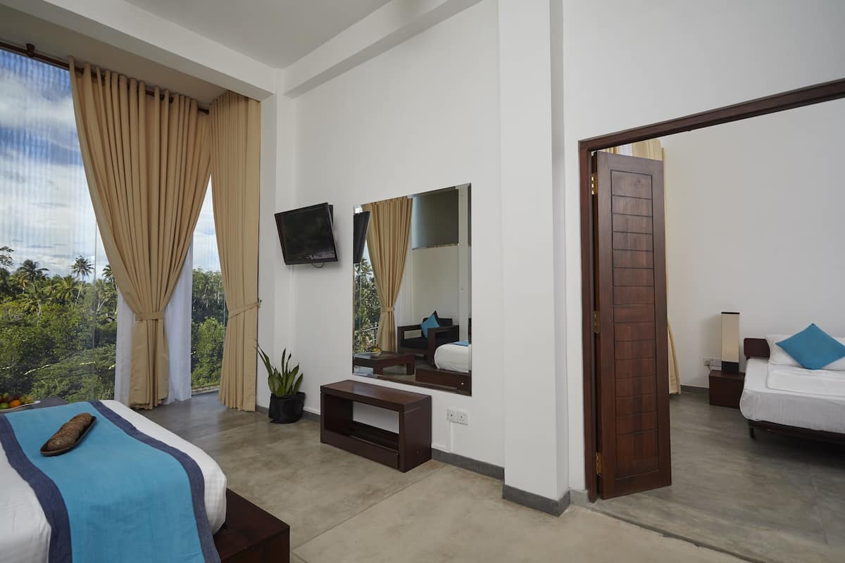 Habitación de hotel moderna con una cama grande, televisión, espejo y vistas al exterior.