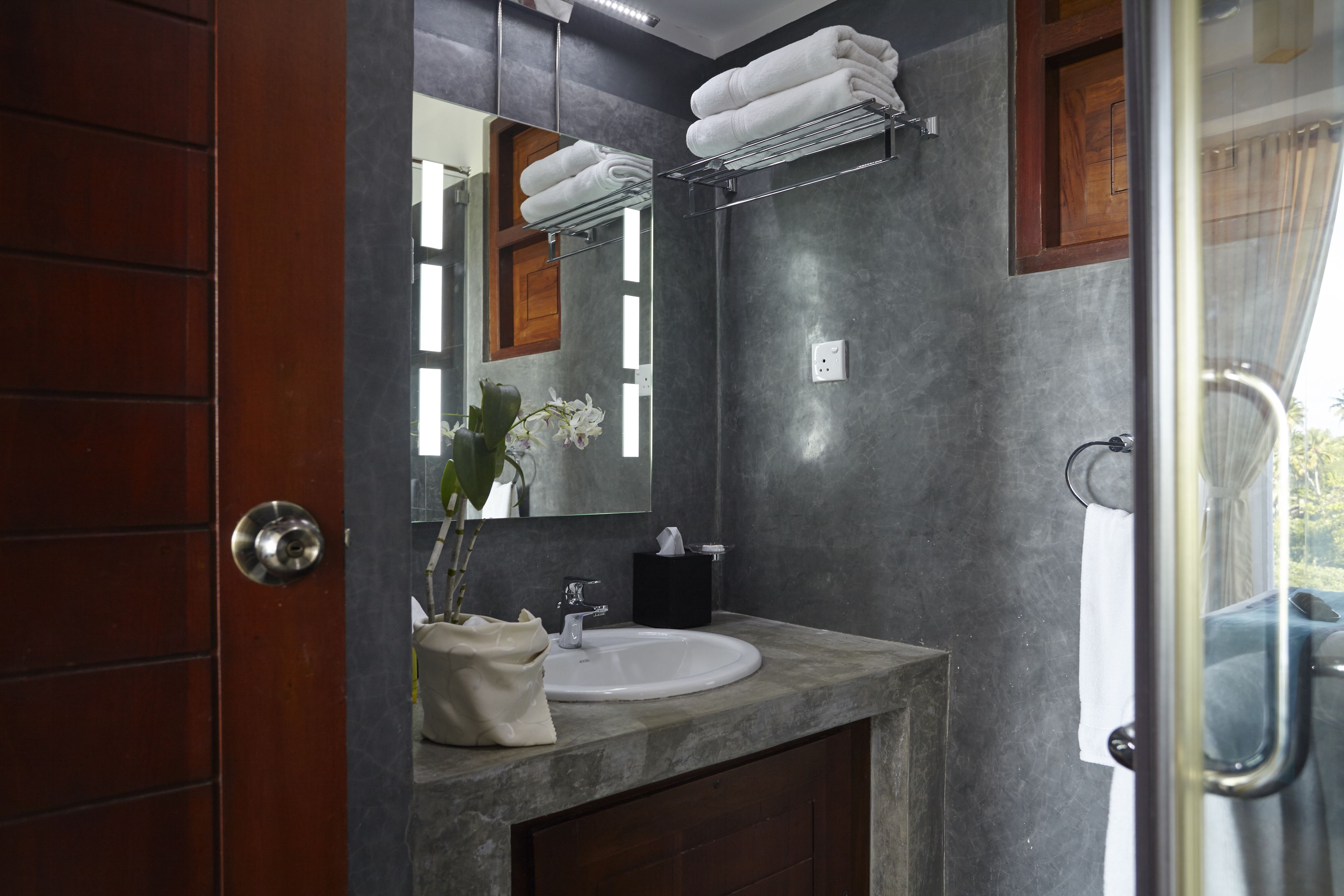 A bathroom with a marble sink, a mirror, a towel rack, and a wooden door.