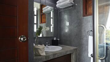 A bathroom with a marble sink, a mirror, a towel rack, and a wooden door.