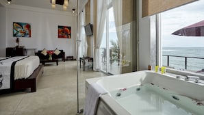 Et moderne hotelværelse med et stort badekar, en seng, et skrivebord og havudsigt.