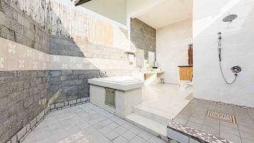 A modern bathroom with a stone wall, a sink, and a shower.