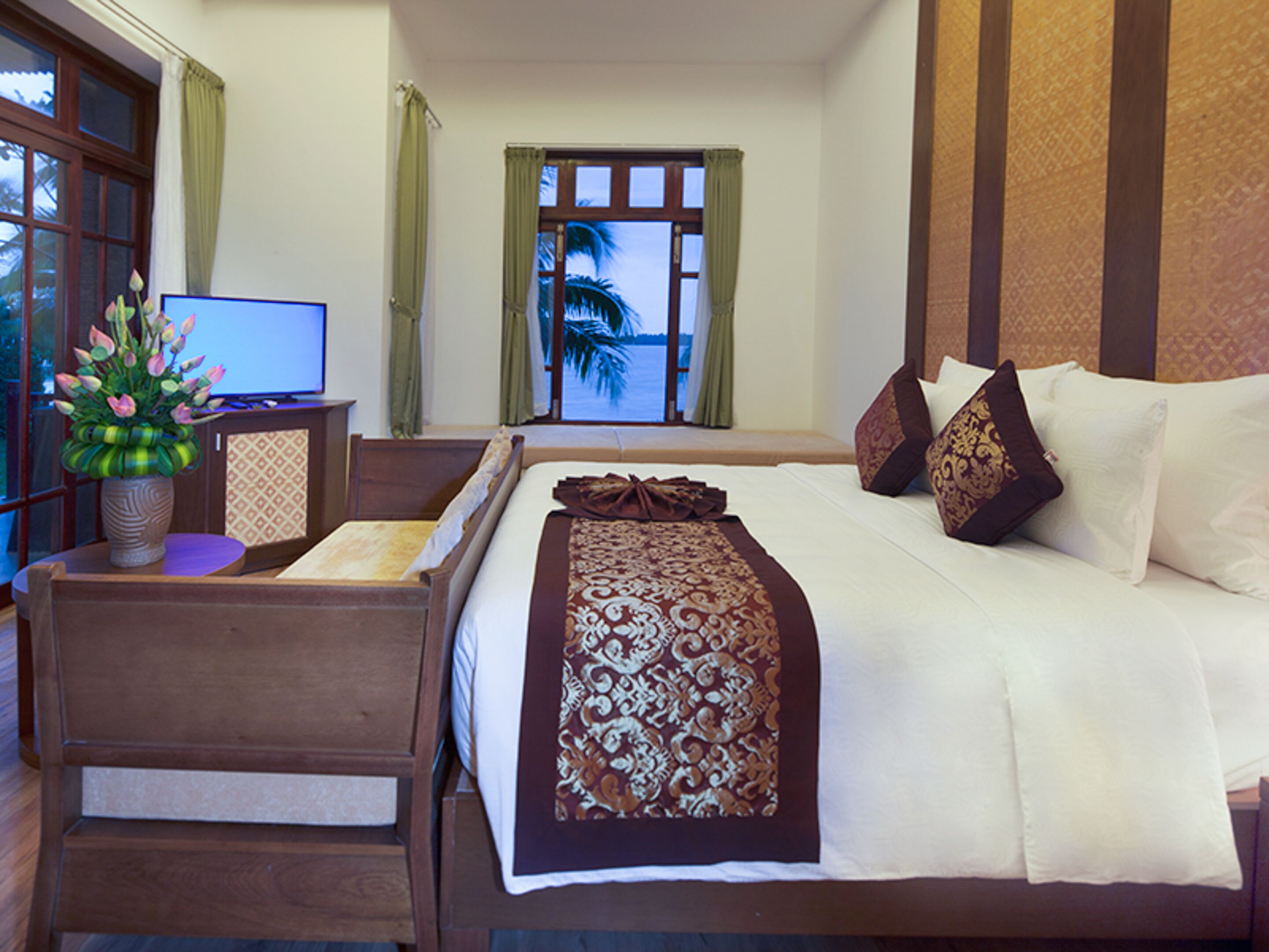 A hotel room with a bed, a desk, a computer, and a view of the outdoors.