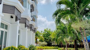 Ein mehrstöckiges Hotel mit Balkonen, einem gepflasterten Weg und üppiger Bepflanzung.