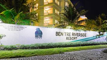The Ben Tre Riverside Resort sign with a stone wall, palm trees, and a building in the background.