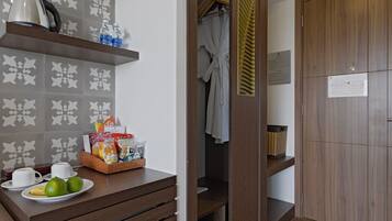 A hotel room with a wooden cabinet, a tray with snacks, a white towel, and a wooden door.