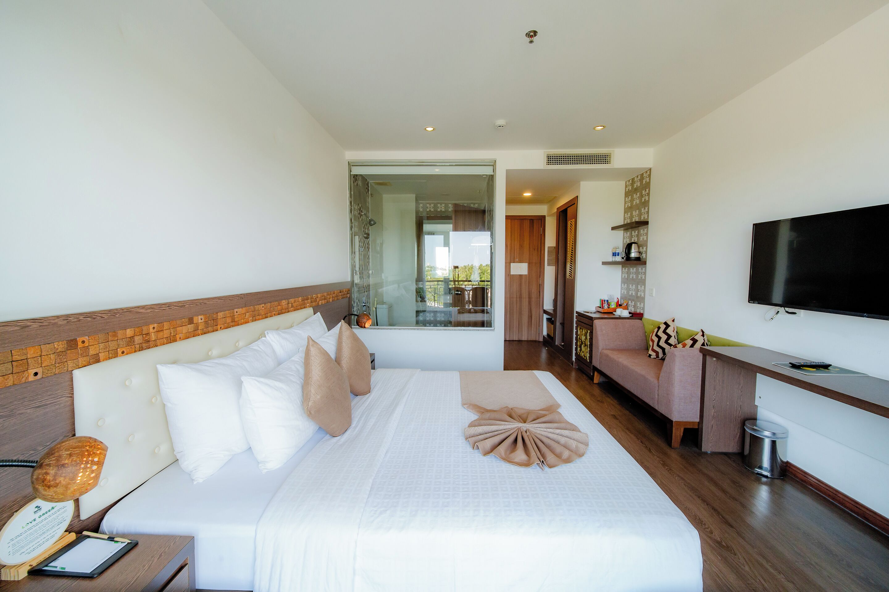 A hotel room with a large bed, a desk with a TV, a sofa, and a view of the outdoors.
