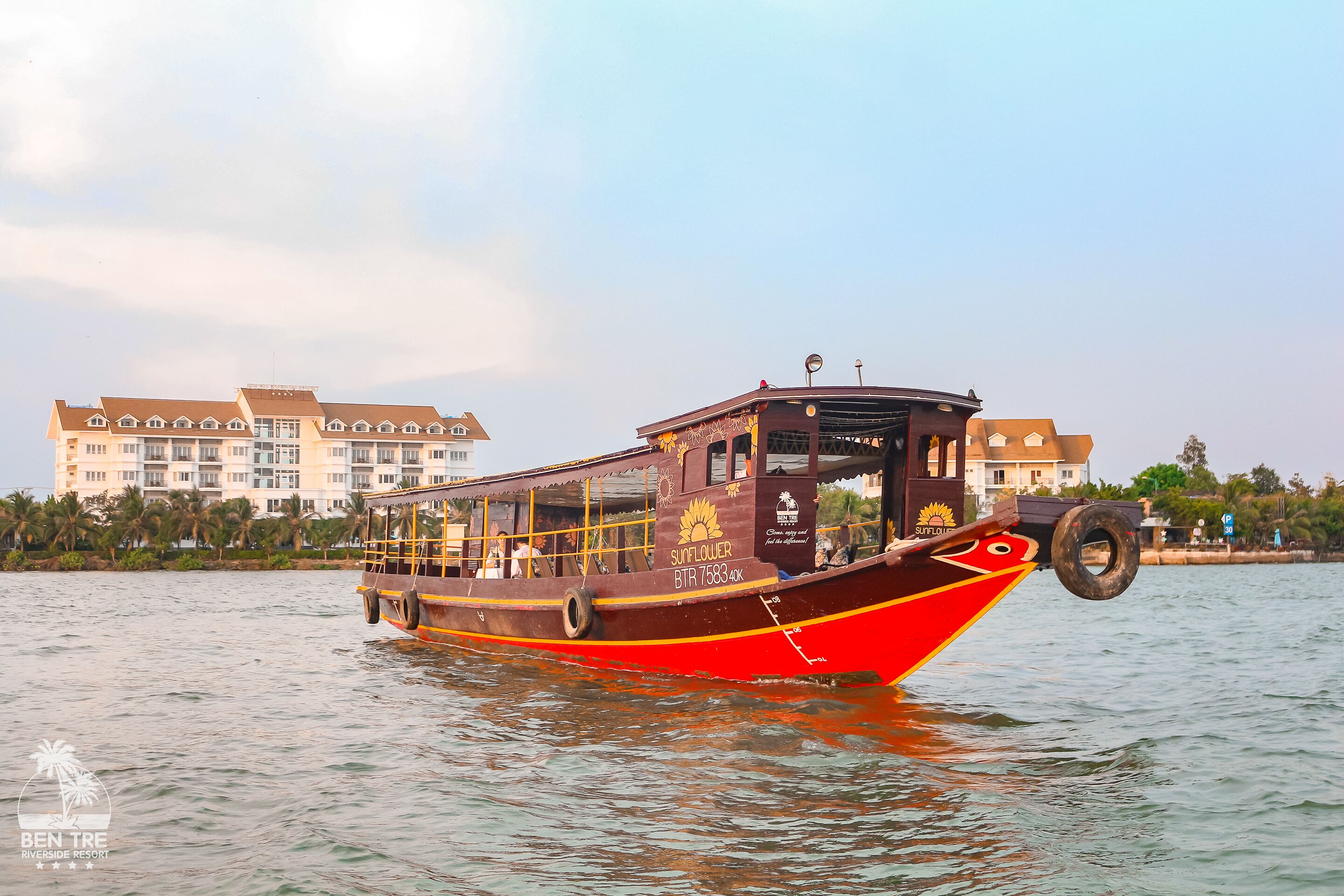 A boat with a cabin and a red hull, floating on water.