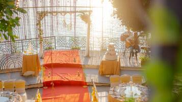 An outdoor wedding setup with a stage, tables, and chairs arranged for guests.