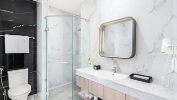 Ein modernes Badezimmer mit einer Duschkabine aus Glas, einer weißen Toilette, einem Waschbecken mit Spiegel und einem Telefon.