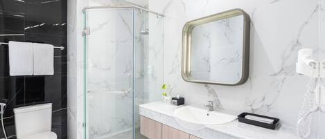 Une salle de bain moderne avec une douche à parois de verre, des toilettes blanches, un meuble-lavabo et un miroir.