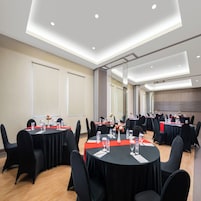 A conference room with round tables, black chairs, and a red tablecloth.