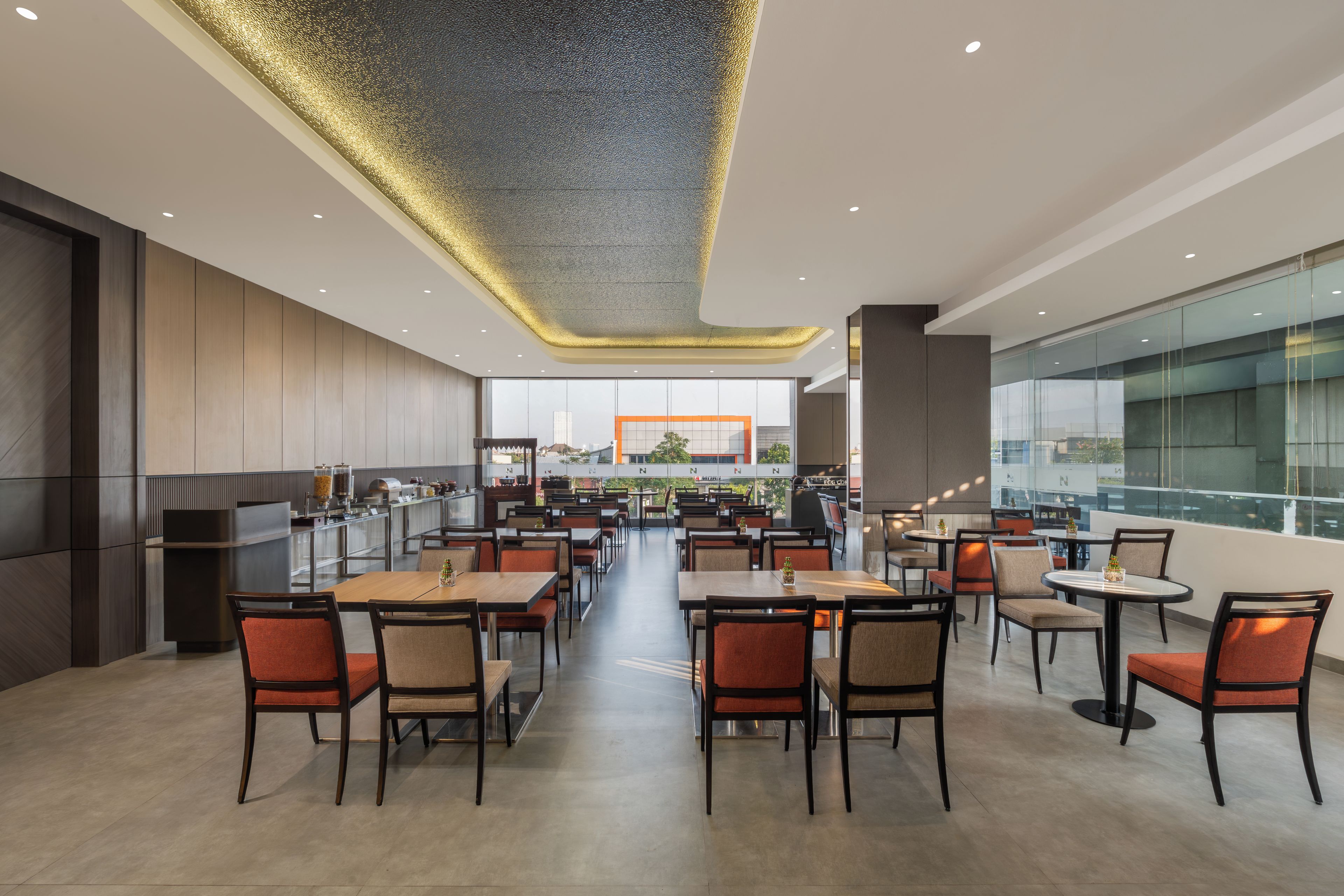 A modern restaurant with a long counter, multiple tables, and chairs.