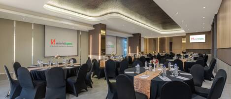 A conference room with tables set for a meeting, equipped with water bottles and notepads.