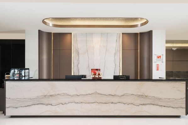 A reception desk with a marble top, a priority check-in sign, and a small dog figurine.