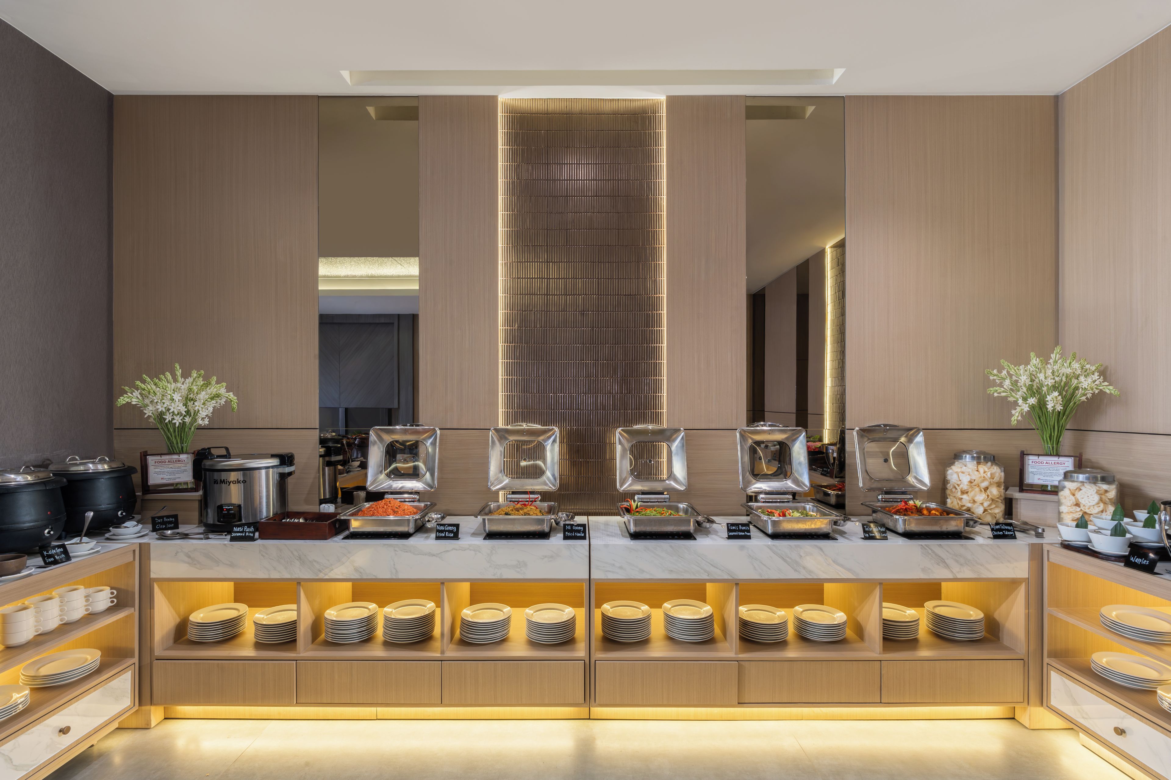 A modern buffet setup with various food stations and a central decorative element.