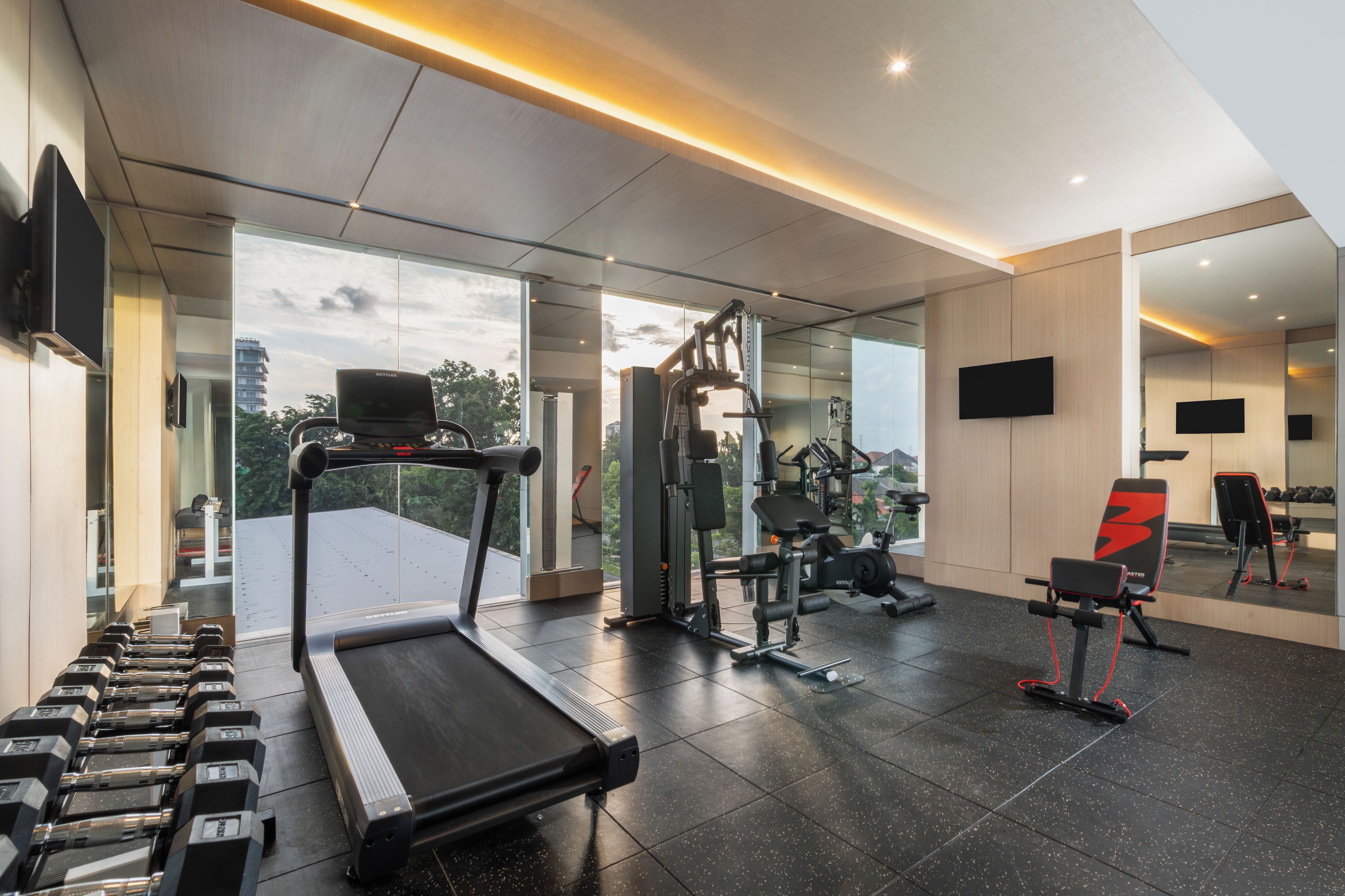 Un gimnasio moderno con cinta de correr, máquinas de pesas y pesas sueltas.