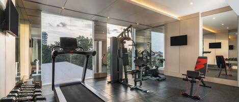 A modern gym with a treadmill, weight machines, and free weights.