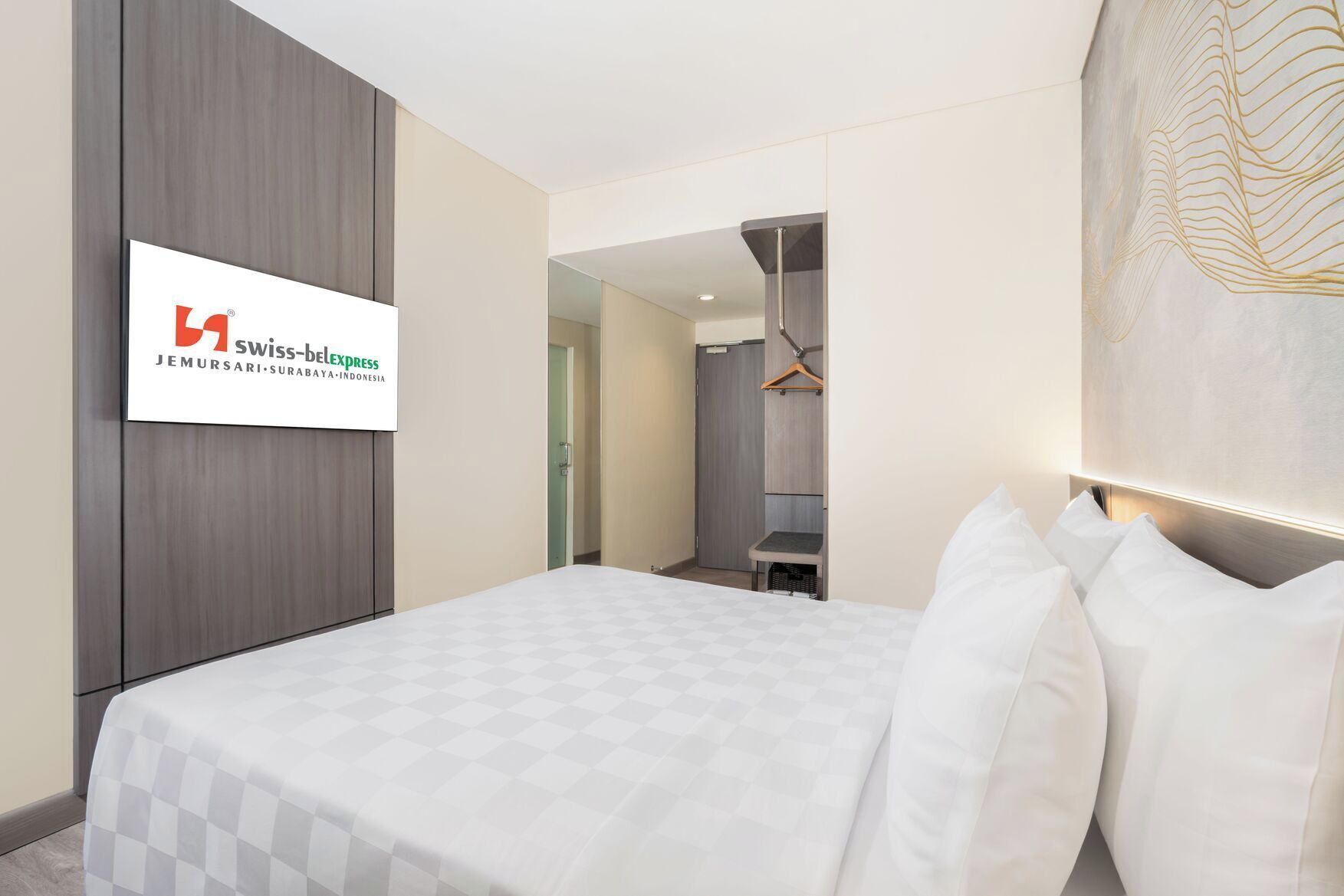 Una habitación de hotel con cama, armario, espejo y perchero.