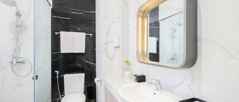 A modern bathroom with a glass shower enclosure, a toilet, a sink, and a large mirror.