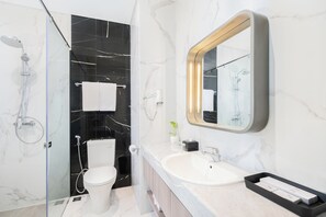 A modern bathroom with a glass shower enclosure, a toilet, a sink, and a large mirror.