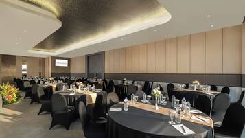 A conference room with round tables, black chairs, and a large screen.