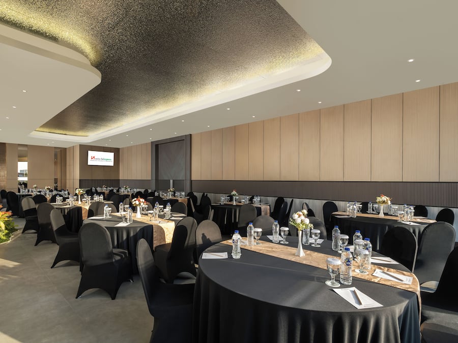 A conference room with round tables, black chairs, and a large screen.