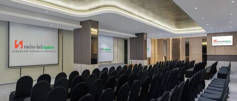 A conference room with rows of chairs, a projection screen, and a modern ceiling design.