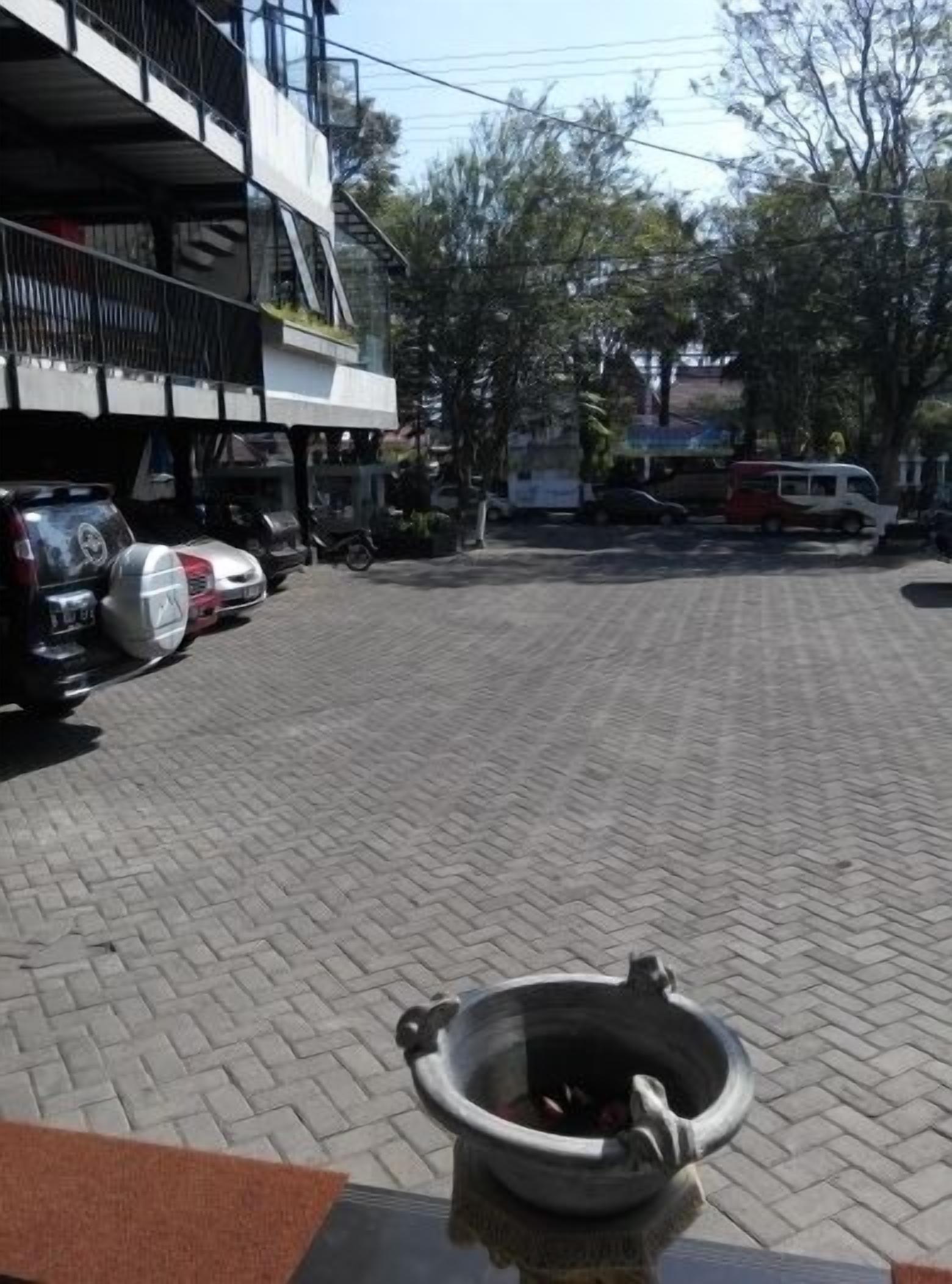Un estacionamiento con un hidrante al frente, un edificio de varios pisos con balcones de fondo y varios vehículos estacionados.