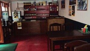 A bar area with a wooden counter, shelves of bottles, and a green carpet. - Metro Eco Hotel (Kathmandu)