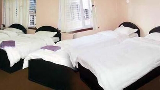 A hotel room with three single beds, each with a black frame and white bedding. - Metro Eco Hotel (Kathmandu)