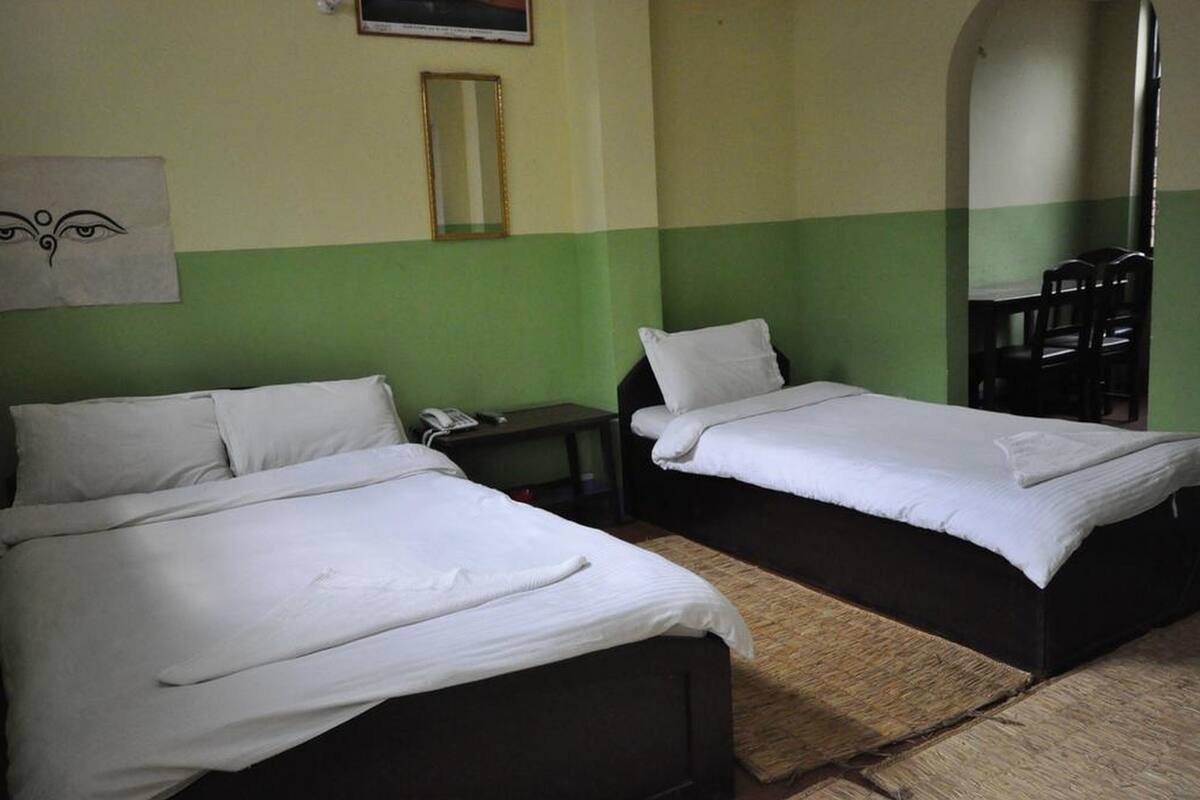 Two single beds with white linens in a room with green and beige walls.