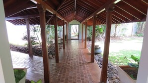 A covered walkway with stone flooring and wooden pillars, leading to a building entrance. - Villa Hundira (Negombo)