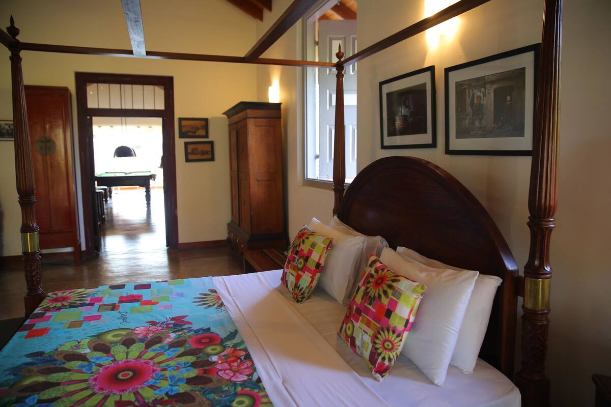 A four-poster bed with colorful pillows, a wooden headboard, and a floral bedspread.