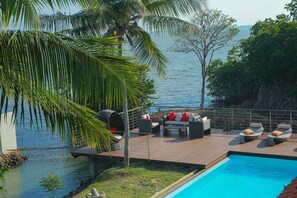 A poolside area with outdoor furniture, a view of the sea, and a wooden deck. - Villa Hundira (Negombo)