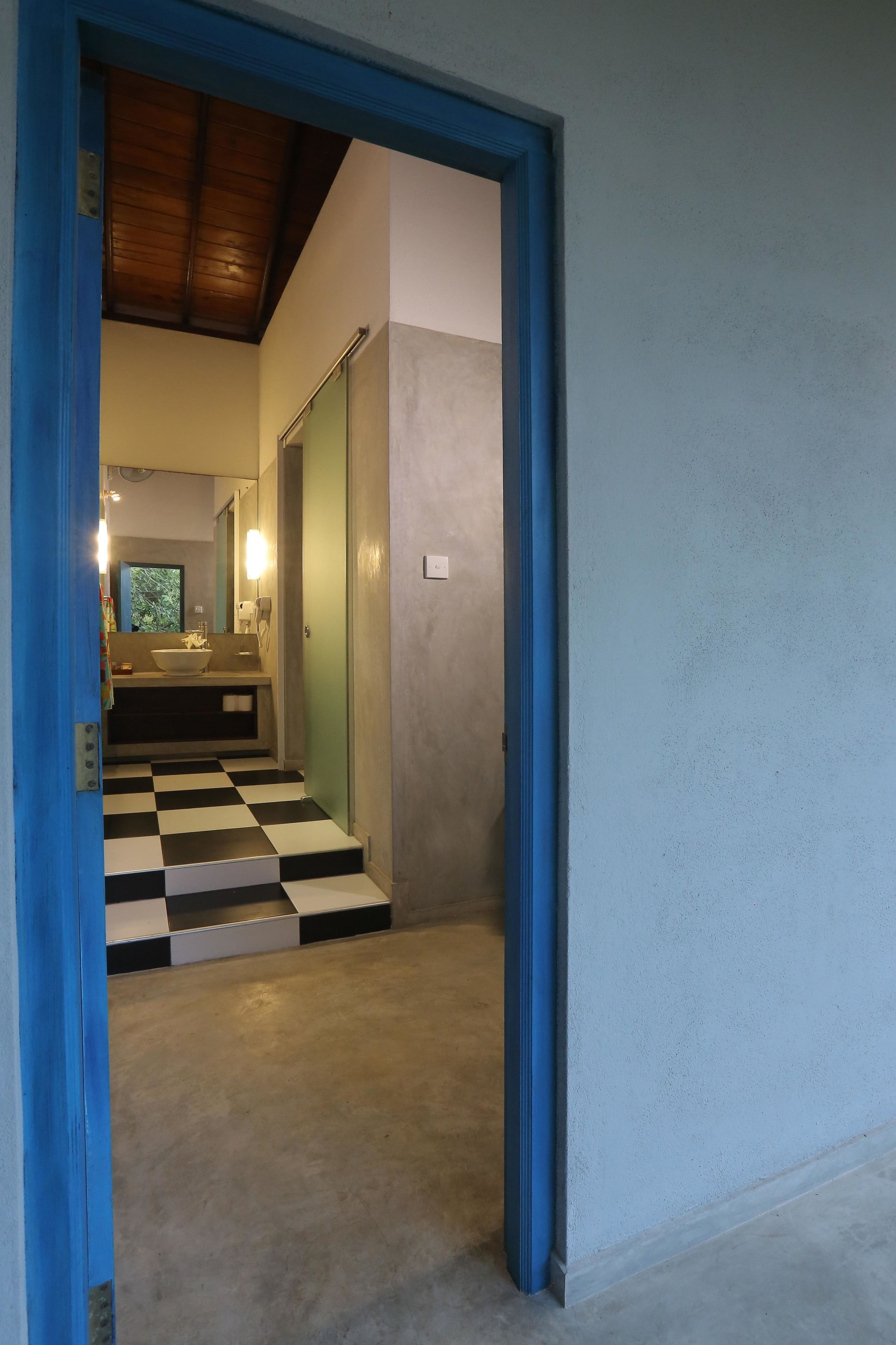 A hallway leading to a bathroom with a checkered floor and a sink.
