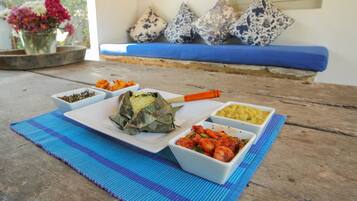 A table with various dishes, a woven mat, and a blue sofa with patterned cushions.
