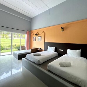 Two single beds with white linens and a dark headboard, set against a large window with a view of a green outdoor area.