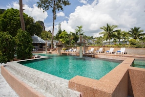 Relax by the serene pool surrounded by lush greenery and palm trees.