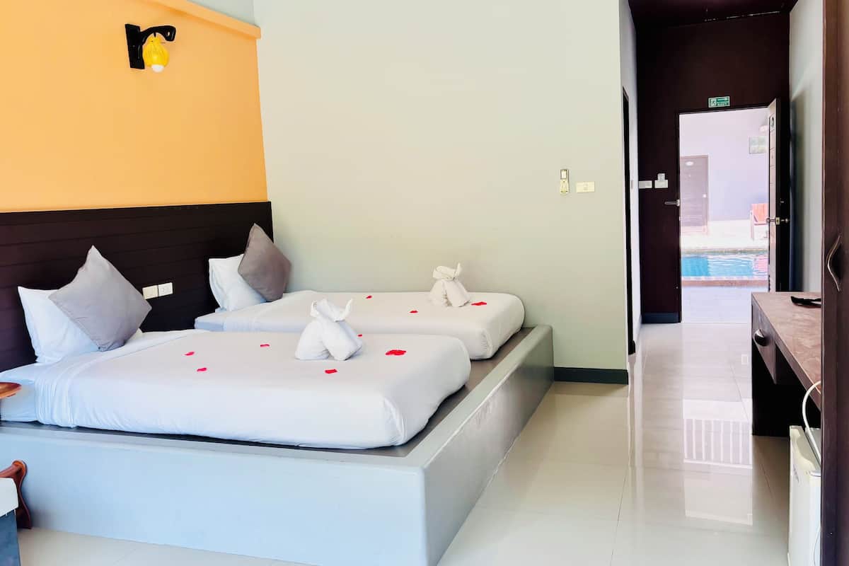 Quarto de hotel com duas camas, cabeceira e vista para a piscina.
