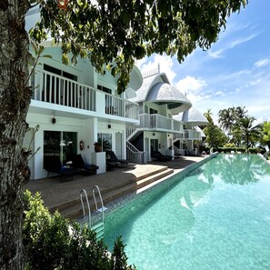 Relax by the large pool surrounded by lush greenery and palm trees.