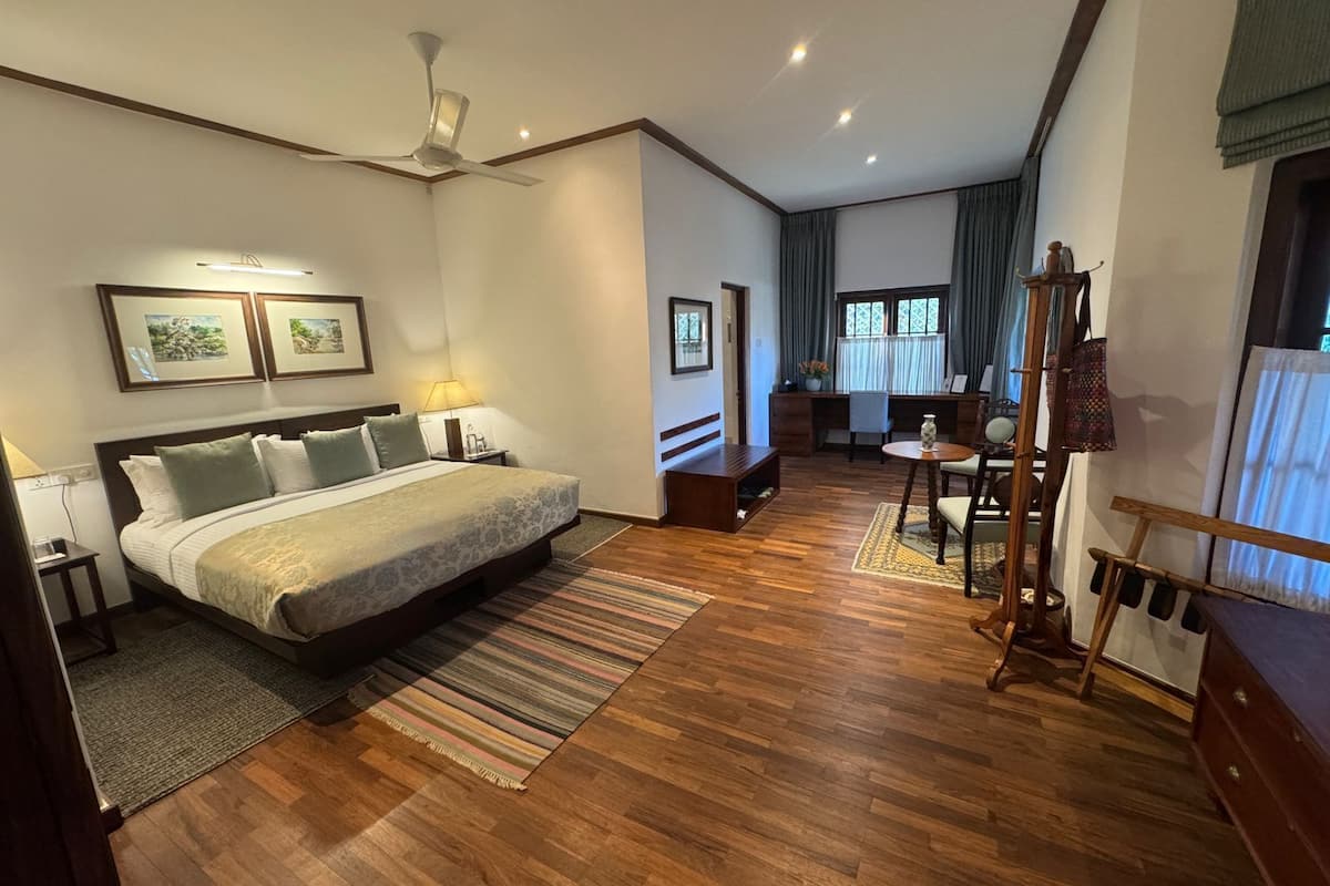 A hotel room with a large bed, a desk, a chair, and a small table.