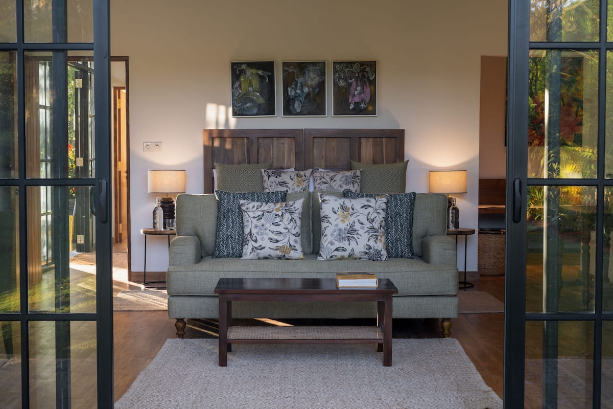 A living room with a sofa, two side tables, a coffee table, and a wooden headboard.