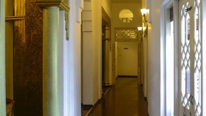 A long, narrow hallway with a polished wooden floor, white walls, and decorative columns. - Deco On 44 (Galle)