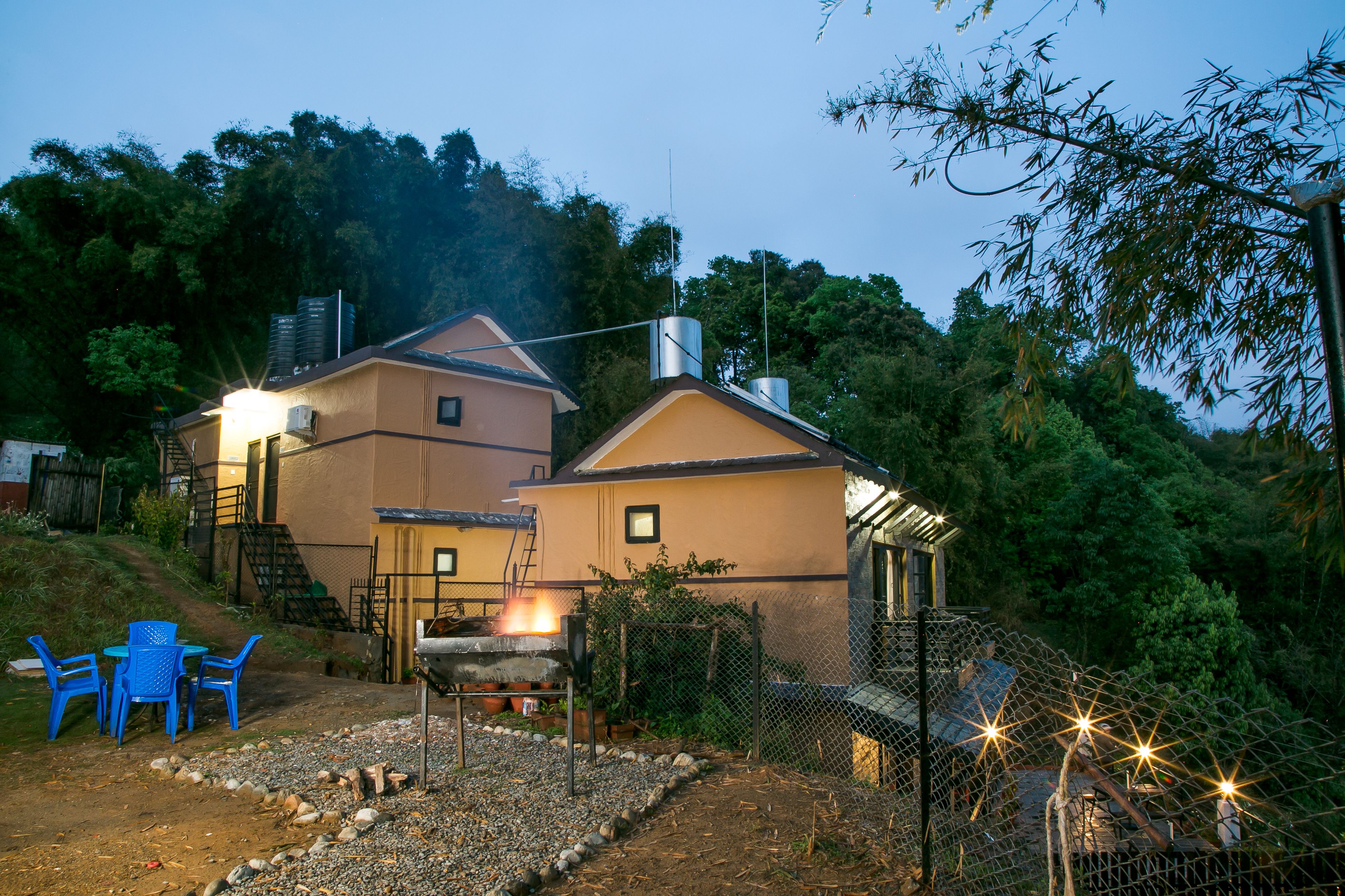 A two-story building with a patio area, outdoor seating, and a fenced garden.