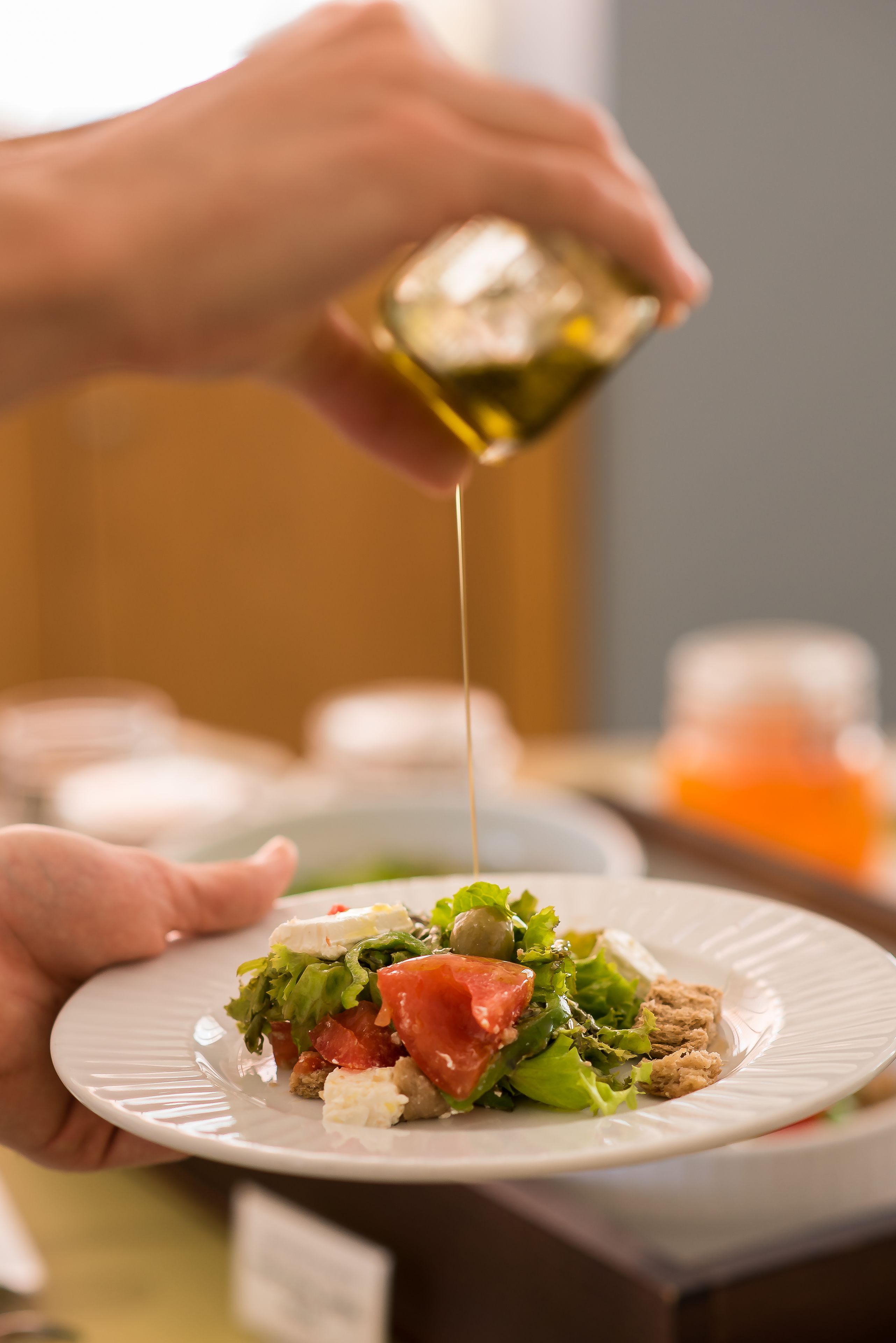 Una persona sirviendo un líquido transparente sobre un plato con ensalada.