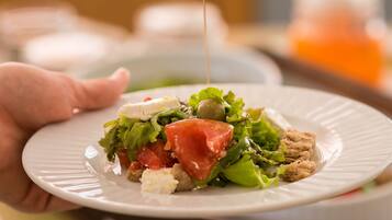 A person pouring a clear liquid onto a plate with a salad.