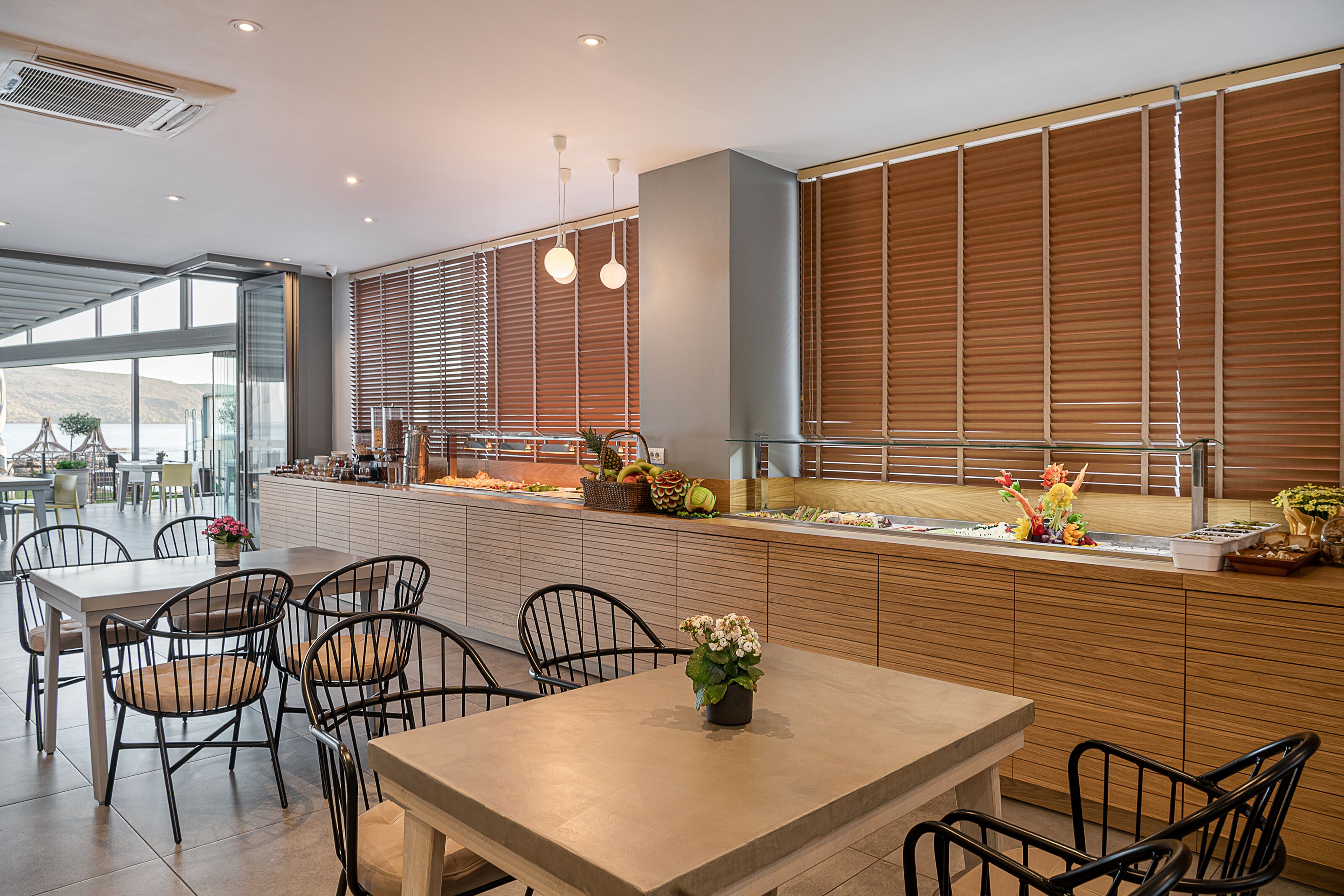 A modern restaurant with a long counter, wooden paneling, and a view of the outdoors.