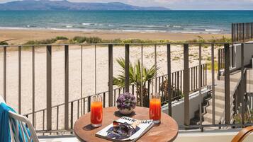 Un balcón con mesa, sillas y vistas a la playa y las montañas.